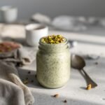 A glass jar filled with creamy green pistachio chia pudding
